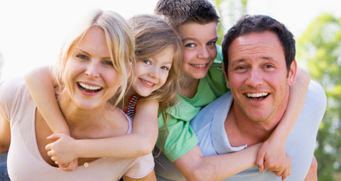 Smiling parents giving their children a piggy back